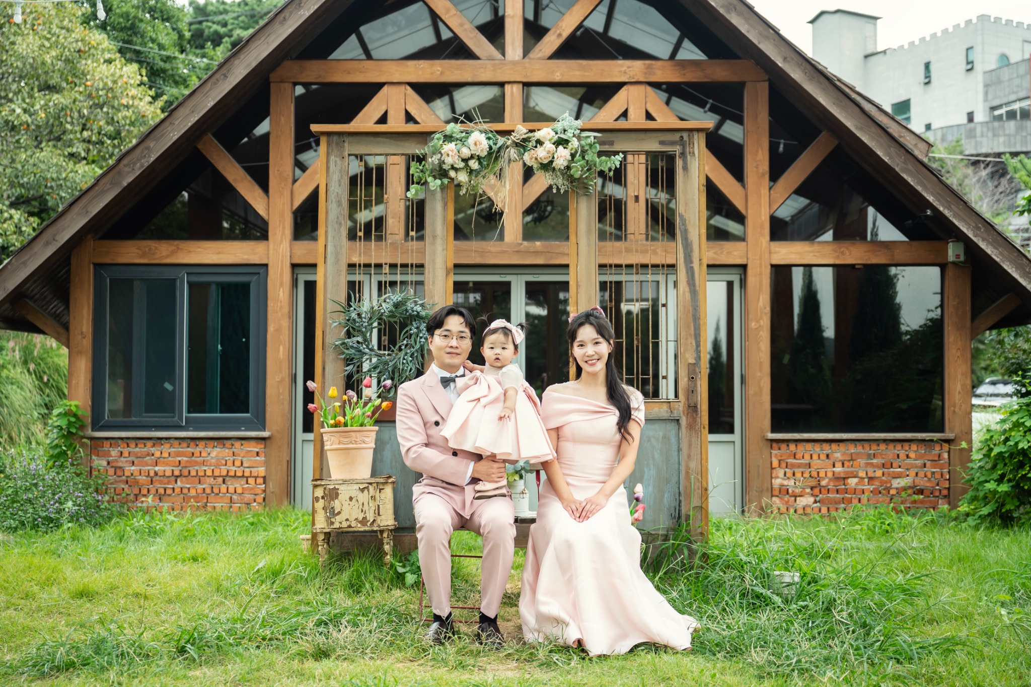 목조 건물 앞에서 촬영한 핑크 톤 가족 돌스냅 사진